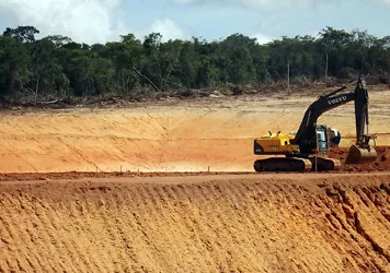 Escavadeira trabalhando em terreno em fase de terraplenagem